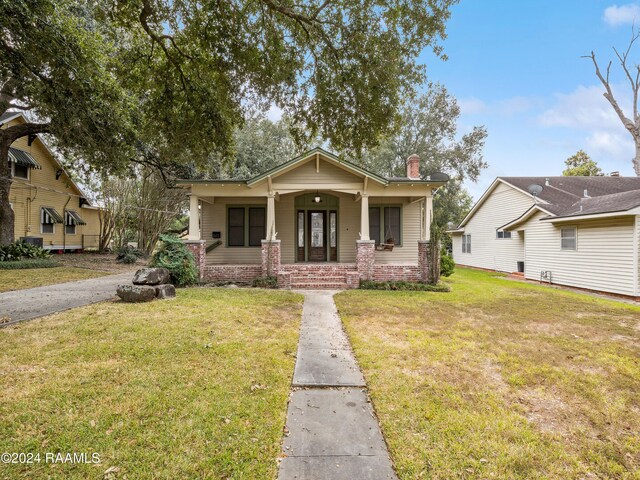 243 W Grolee St, Opelousas, LA 70570 - view of front of house featuring a porch, a front lawn, and a chimney