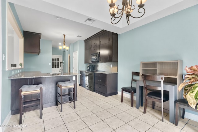 kitchen featuring sink, an inviting chandelier, backsplash, a kitchen breakfast bar, and black appliances