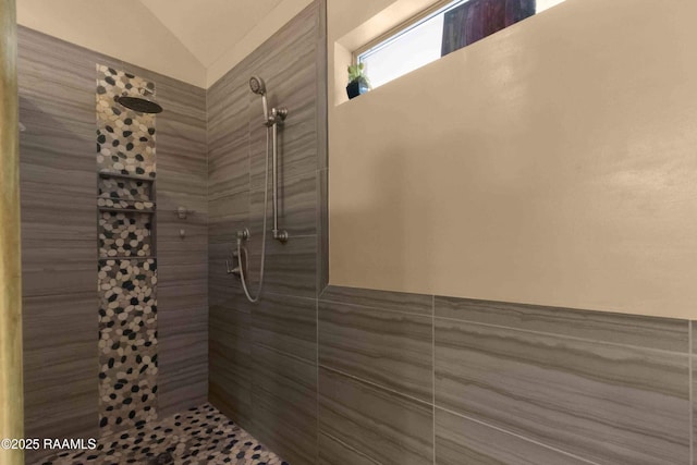 bathroom with vaulted ceiling and a tile shower