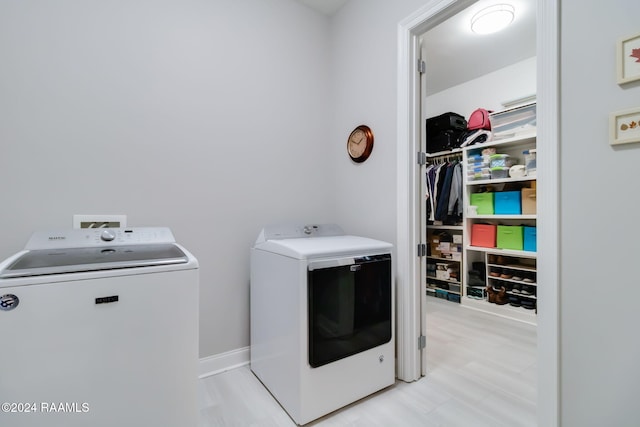 laundry area with independent washer and dryer and light hardwood / wood-style floors