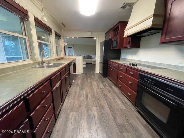 kitchen with sink, black appliances, custom range hood, and wood-type flooring