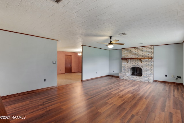 unfurnished living room featuring a brick fireplace, hardwood / wood-style flooring, ceiling fan, and crown molding