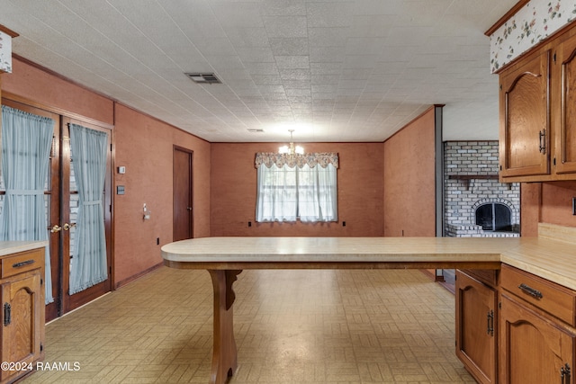 kitchen with kitchen peninsula, light parquet flooring, hanging light fixtures, a notable chandelier, and a brick fireplace