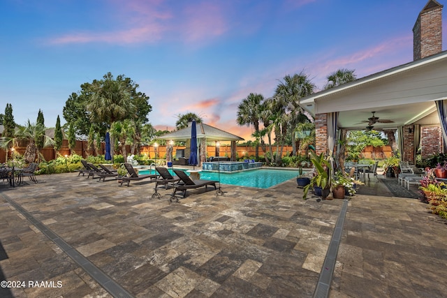 pool at dusk with a patio, a gazebo, and ceiling fan