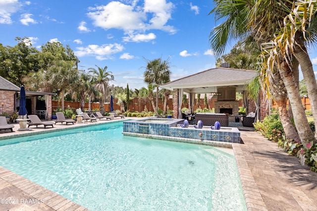 view of swimming pool featuring exterior fireplace, ceiling fan, a patio, and an in ground hot tub