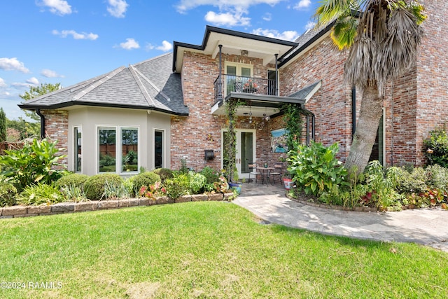 view of front of house featuring a front lawn and a balcony