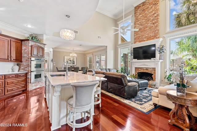 kitchen featuring a towering ceiling, sink, an island with sink, double oven, and a breakfast bar