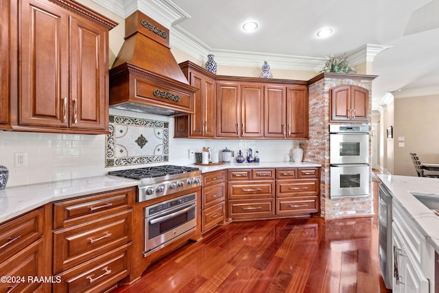 kitchen featuring light stone counters, ornamental molding, appliances with stainless steel finishes, custom range hood, and dark hardwood / wood-style flooring