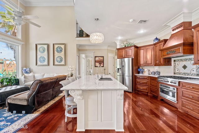 kitchen featuring dark wood-type flooring, sink, a kitchen island with sink, a breakfast bar, and appliances with stainless steel finishes