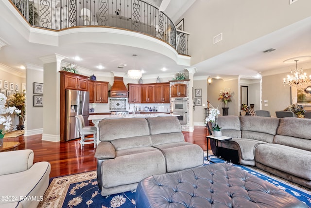 living room featuring a high ceiling, ornamental molding, a chandelier, and dark hardwood / wood-style floors