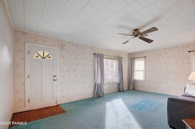 carpeted foyer entrance with ceiling fan and ornamental molding