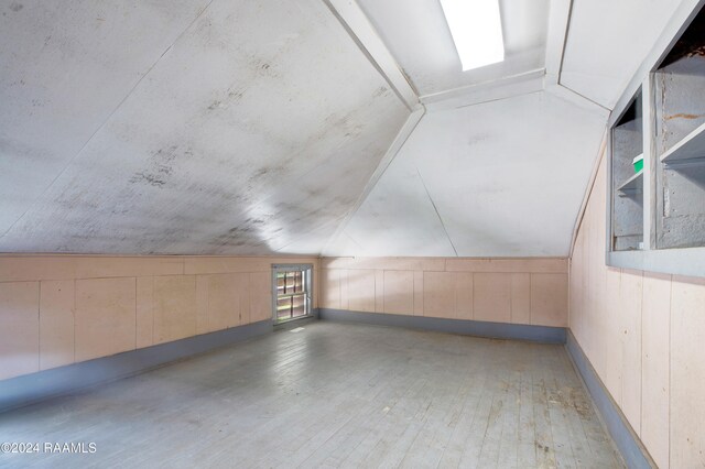 bonus room with hardwood / wood-style floors, wood walls, and lofted ceiling