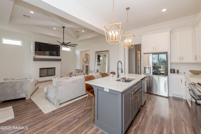 kitchen featuring a center island with sink, appliances with stainless steel finishes, sink, white cabinets, and dark wood-type flooring