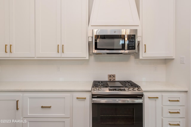 kitchen featuring stainless steel appliances, light stone countertops, white cabinets, and decorative backsplash