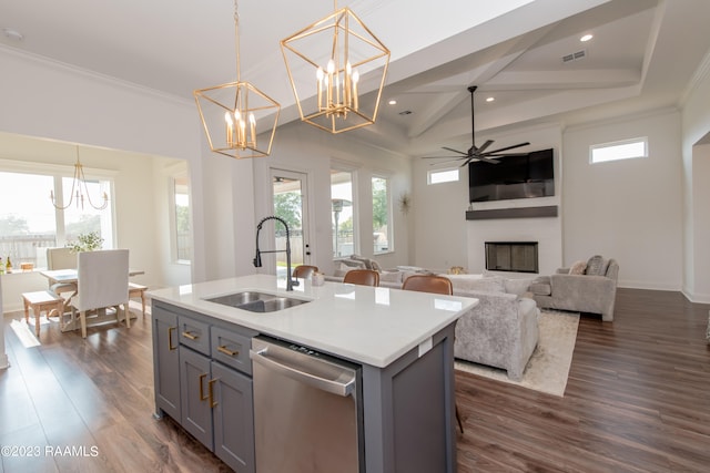 kitchen with hanging light fixtures, stainless steel dishwasher, sink, and an island with sink