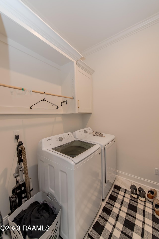 washroom with cabinets, crown molding, and washing machine and clothes dryer