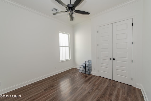 unfurnished bedroom with dark wood-type flooring, ceiling fan, a closet, and crown molding