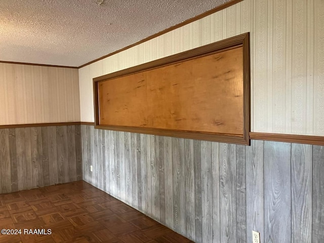 unfurnished room featuring crown molding, dark parquet flooring, a textured ceiling, and wooden walls