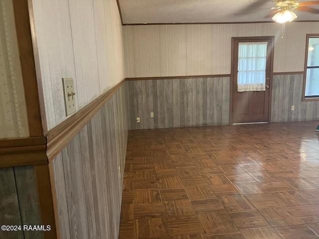 spare room with dark parquet flooring, a textured ceiling, and wood walls