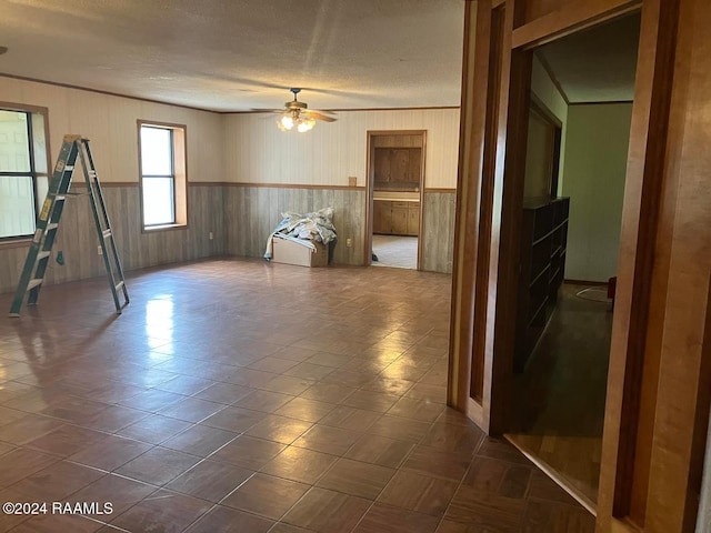 unfurnished room with ceiling fan, wooden walls, and ornamental molding