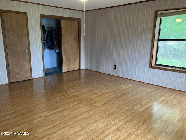 empty room with light wood-type flooring and crown molding