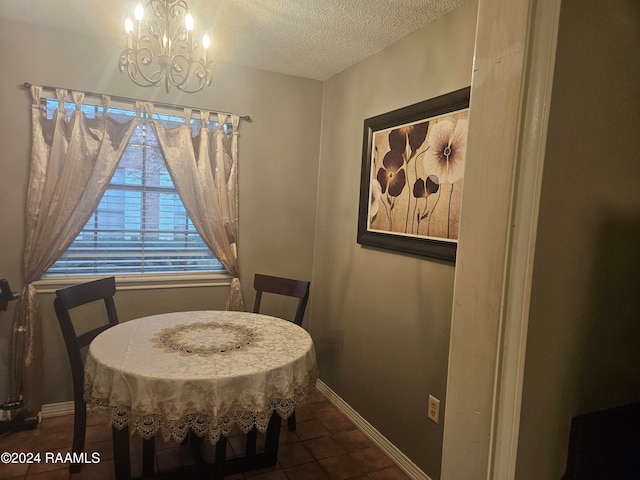 dining area with a textured ceiling, dark tile patterned flooring, and a notable chandelier