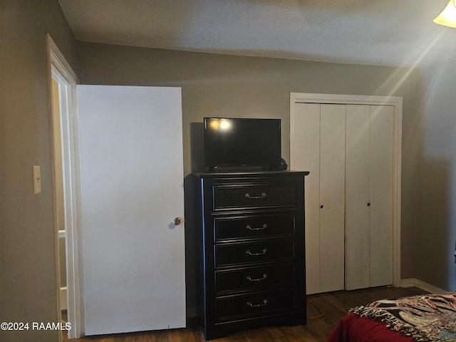 bedroom featuring dark wood-type flooring, a closet, and a textured ceiling