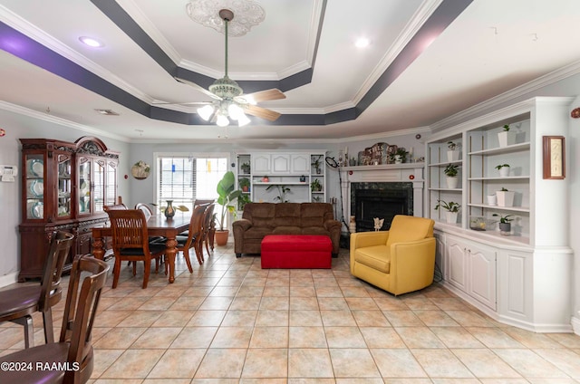 tiled living room with ceiling fan, a raised ceiling, and ornamental molding