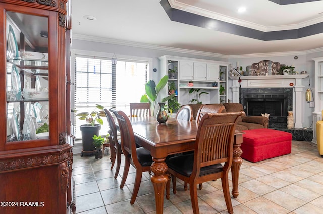 tiled dining area featuring a high end fireplace, a tray ceiling, and ornamental molding