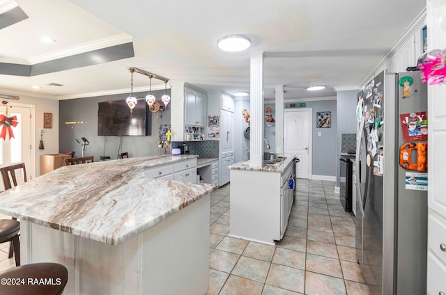 kitchen with a kitchen breakfast bar, backsplash, crown molding, a center island, and stainless steel refrigerator