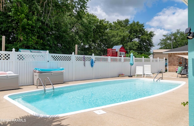 view of swimming pool featuring a hot tub and a patio area