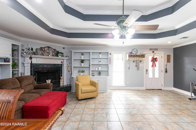 living room with a tray ceiling, crown molding, and a high end fireplace