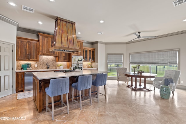 kitchen featuring tasteful backsplash, a large island with sink, ornamental molding, custom range hood, and stainless steel appliances