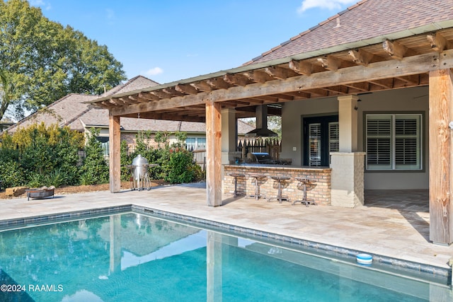 view of swimming pool featuring exterior bar and a patio