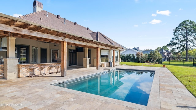 view of swimming pool featuring a patio, exterior bar, a yard, and ceiling fan