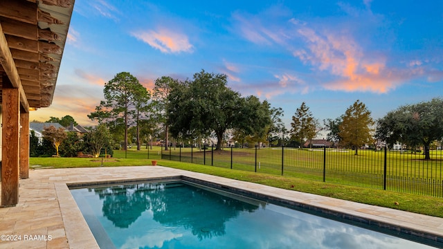 pool at dusk with a yard and a patio area