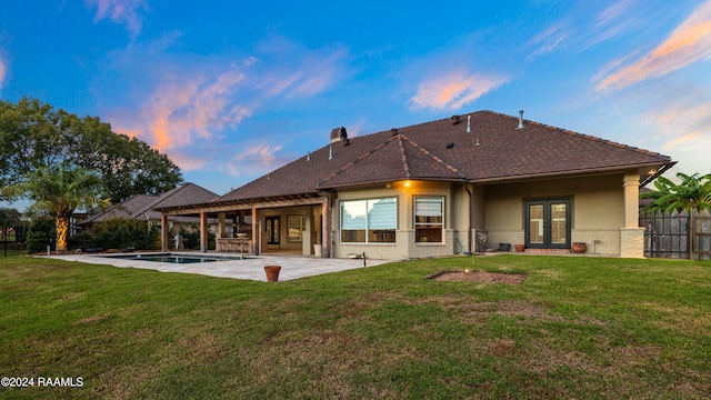 back house at dusk featuring a fenced in pool, a yard, a patio area, and french doors