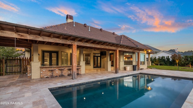 back house at dusk with a patio, an outdoor bar, and ceiling fan