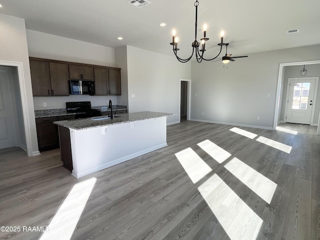 kitchen featuring sink, an island with sink, light hardwood / wood-style flooring, and black appliances