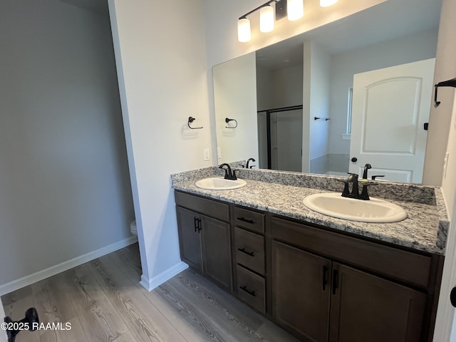 bathroom featuring toilet, vanity, a shower with door, and hardwood / wood-style floors