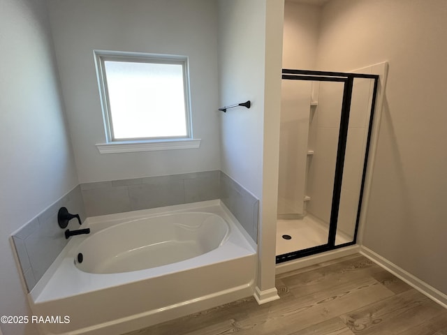 bathroom featuring plus walk in shower and hardwood / wood-style flooring