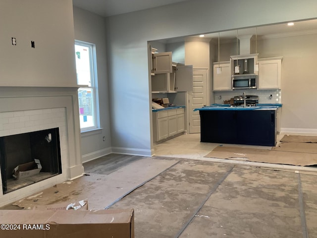 kitchen with white cabinets, a healthy amount of sunlight, appliances with stainless steel finishes, and a brick fireplace