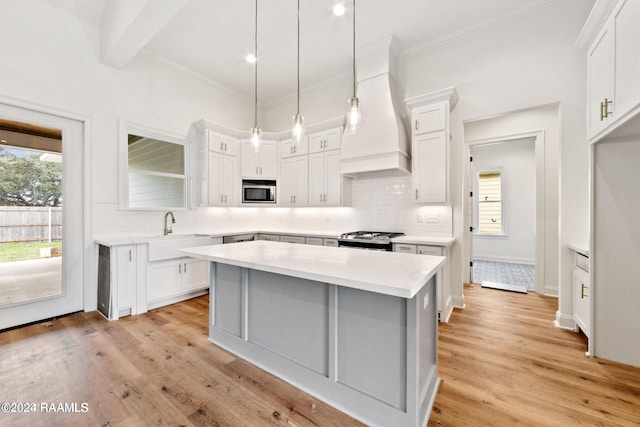 kitchen featuring white cabinets, light wood-type flooring, a kitchen island, and custom range hood