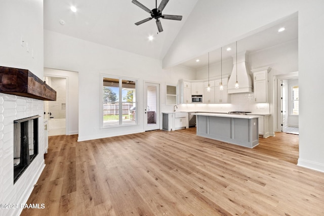 kitchen with a center island, white cabinets, custom exhaust hood, high vaulted ceiling, and pendant lighting