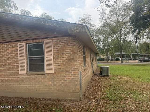 view of side of property featuring central AC and a yard