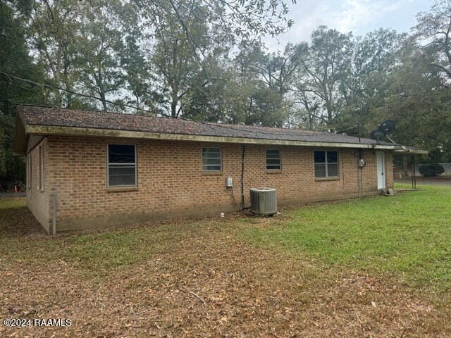 back of property featuring central AC unit and a lawn