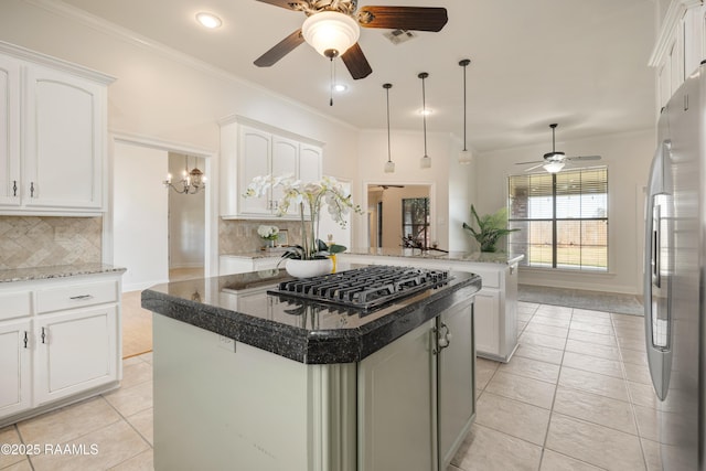 kitchen featuring crown molding, stainless steel appliances, a center island, white cabinets, and decorative backsplash