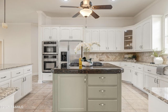 kitchen with stainless steel appliances, a kitchen island, white cabinets, and light stone counters