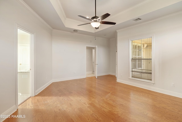 empty room featuring a tray ceiling, light hardwood / wood-style flooring, ornamental molding, and ceiling fan