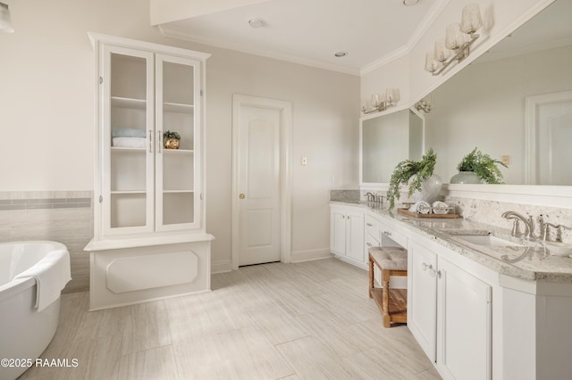 bathroom with vanity, crown molding, and a tub